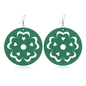 Detail of green wooden hollow flower earrings with silver hooks on white background