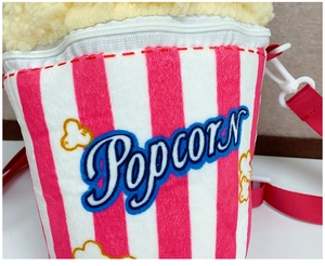 Detail of plush popcorn crossbody bag featuring red and white stripes and embroidery