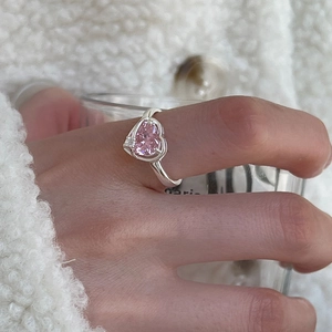 Close-up of silver ring featuring heart-shaped pink gemstone on model hand