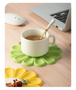 Daisy flower silicone heat-resistant mats in green and yellow on a modern desk