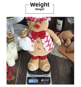 Detail showing plush gingerbread man doll weighted at 446g on scale with festive decor
