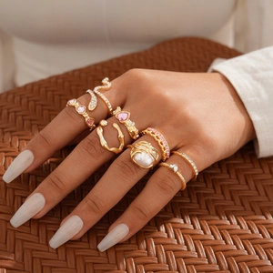 Eight-piece gold ring set with pink heart gems and pearls worn on a model's hand