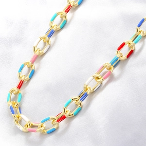 Detail of chunky gold chain necklace with vibrant colorful enamel links on white silk