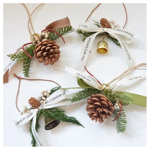 Detailed view of handmade Christmas pine cone hanging ornaments with bells and ribbons