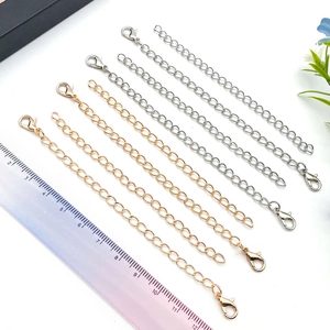 Golden and silver metal extender chains with lobster clasps shown with a scale ruler