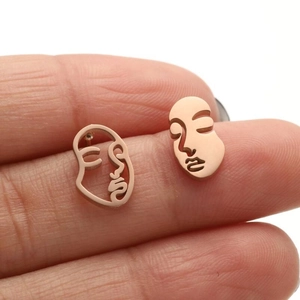 Abstract wire face earrings in rose gold finish held to show artistic hollow design