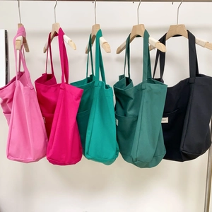 Close-up showing the multiple color options and canvas texture of the tote bag