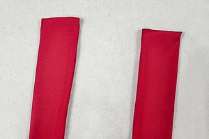 Makro-Detail des roten Twill-Gewebes mit präzisen Nähten an den Trägern des Kleides