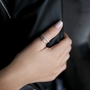 Close-up of a 925 sterling silver T-shaped ring and zircon-set band on a hand
