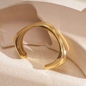Macro shot of gold wavy irregular open cuff bracelet on geometric stone background