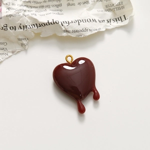 Macro detail of a dark red melting heart pendant with a polished gold hanging loop
