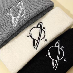 Three warm knit beanies in grey, white, and black colors with planet embroidery