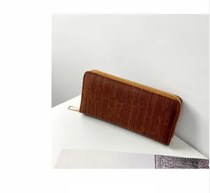 Detail of a dark brown striped long wallet with a golden metal zipper closure