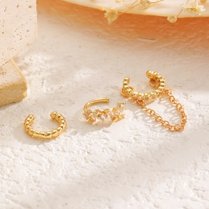 Detalle del conjunto de tres pendientes dorados con circonitas y cadenas decorativas