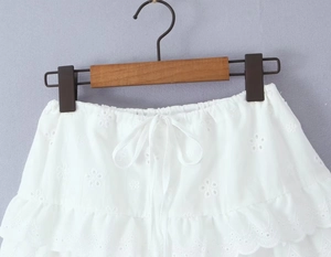 Détail de la jupe blanche à volants avec broderie florale et taille élastique à cordon