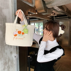 Detailed embroidery of rabbit and flowers on a white quilted canvas tote bag