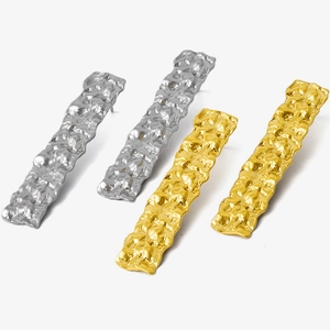 Detailed view of long rectangle earrings with hammered texture in gold and silver finish