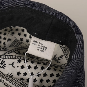 Denim beret interior tag showing 57cm size and hemp lyocell cotton blend details