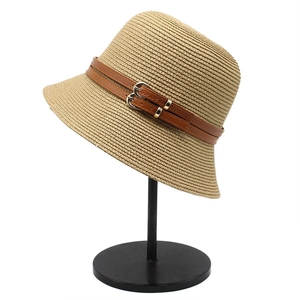 Close-up of tightly woven straw sun hat with brown leather strap and double metal buckle