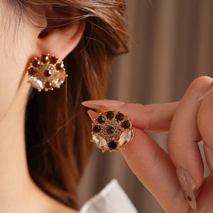 Detailed close-up of vintage flower earrings with dark red crystals in gold finish