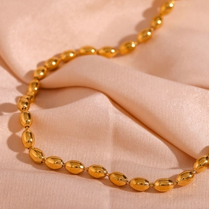 Detailed macro view of 18K gold plated oval bead chain necklace on soft silk