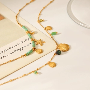 Detail of 18K gold starfish and shell pendants with turquoise beads on necklaces