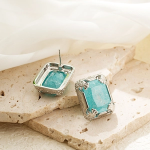 Macro shot of 18K gold vintage earrings with blue gemstones on beige stone and silk