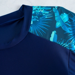 Détail du col rond et de l'imprimé tropical sur un maillot de bain bleu marine à manches