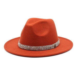 Close-up of orange wool fedora with rhinestone band and metallic letter M detail