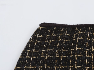 Dettaglio macro del tessuto tweed nero con trama dorata a quadri e orlo bordato nero