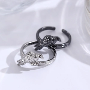 Detail of adjustable silver and black bird rings featuring intricate feather texture engraving