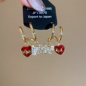 Detail of gold plated hoop earrings with red enamel hearts and rhinestone dog charms