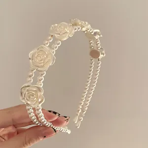 Detail of elegant double-layered faux pearl headband with intricate white resin roses