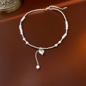 Close-up of silver heart necklace with faux pearls on a brown textured background