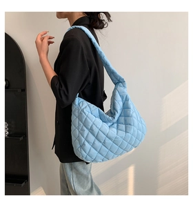 Sky blue quilted tote bag shown on shoulder, highlighting the large capacity and texture