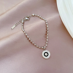 Detail of silver beaded bracelet with black and white zircon circle pendant on pink satin