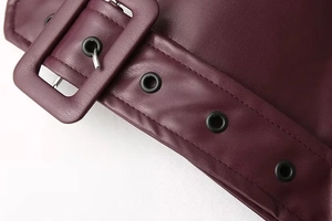 Macro shot of burgundy leather jacket waist belt with metal eyelets and litchi texture