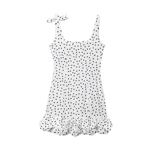 Détail de robe blanche à pois avec taille nouée et ourlet à volants superposés