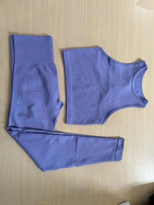 Flach liegendes lilafarbenes nahtloses Rippstrick-Sportset mit Top und hoher Leggings