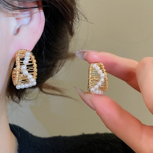 Detail of 18k gold plated C-shape earrings with woven wire and small white pearls