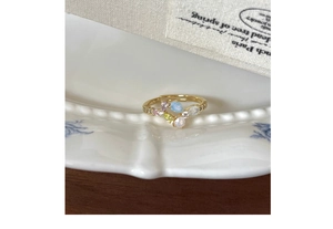 Detail of floral S925 silver ring with multi-colored pear-cut gems on vintage porcelain