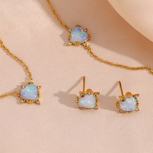 Golden heart-shaped opal jewelry set including necklace and earrings on silk background