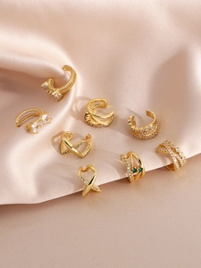 Detailed set of 8 gold ear cuffs with cubic zirconia on champagne silk background