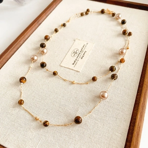 Detail of layered gold necklace with tiger eye stone and pearls on display