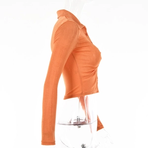 Side view of orange long sleeve cropped top with lapel collar on clear mannequin