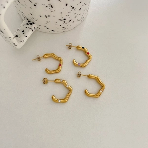 Gold plated wave earrings set with multicolored crystals on a clean white surface