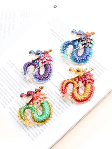 Detail of four colorful dragon enamel brooches with drip oil finish on a magazine