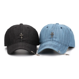 Detailed close-up of denim baseball caps with vintage metal cross and pin accents