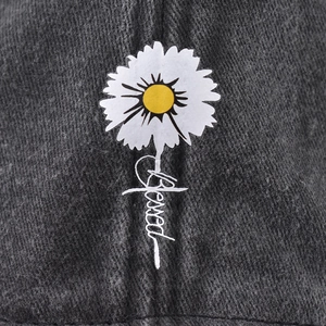 Washed grey denim baseball cap featuring a white daisy and 'Blessed' embroidery text