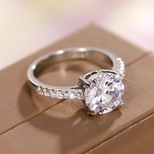 Macro detail of silver-tone six-prong bridal ring with round zircon on jewelry box